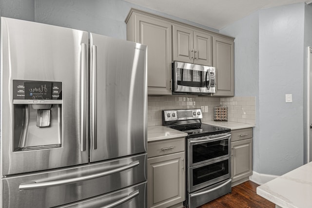 2433 Mallard Dr, Little Elm, TX 75068 - kitchen featuring appliances with stainless steel finishes, gray cabinetry, backsplash, and dark wood-type flooring