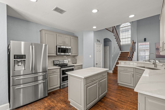 2433 Mallard Dr, Little Elm, TX 75068 - kitchen with appliances with stainless steel finishes, a sink, gray cabinets, decorative backsplash, and dark wood finished floors
