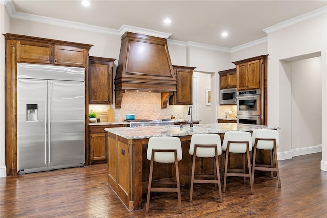 655 Creekway Dr, Irving, TX 75039 - kitchen with built in appliances, custom exhaust hood, an island with sink, tasteful backsplash, and dark wood-type flooring