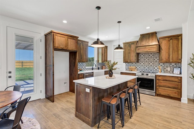 416 Redbud Ln, Tolar, TX 76476 - kitchen with stainless steel appliances, custom range hood, light countertops, decorative backsplash, and light wood-type flooring