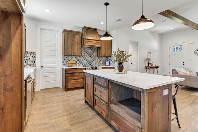 416 Redbud Ln, Tolar, TX 76476 - kitchen featuring custom exhaust hood, tasteful backsplash, light wood-style floors, a breakfast bar area, and decorative light fixtures