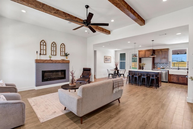 416 Redbud Ln, Tolar, TX 76476 - living room featuring light wood finished floors, recessed lighting, beamed ceiling, a glass covered fireplace, and baseboards
