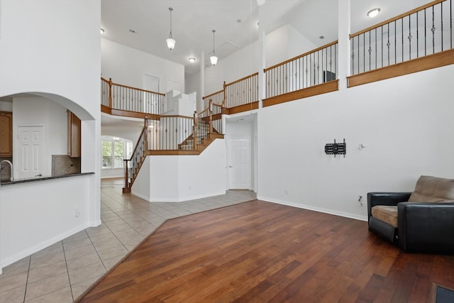 2410 Honey Dr, Arlington, TX 76001 - unfurnished living room with a high ceiling, stairs, arched walkways, and wood finished floors