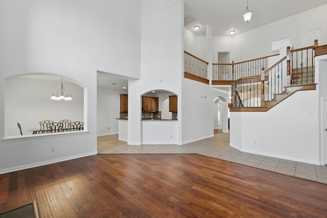 2410 Honey Dr, Arlington, TX 76001 - unfurnished living room with hardwood / wood-style flooring, arched walkways, stairs, a towering ceiling, and a chandelier