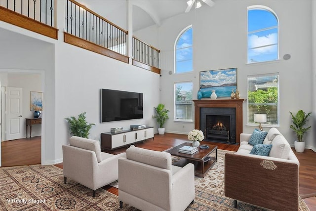 2410 Honey Dr, Arlington, TX 76001 - living room with a high ceiling, wood finished floors, a warm lit fireplace, and a ceiling fan