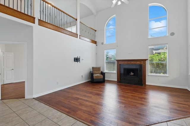2410 Honey Dr, Arlington, TX 76001 - unfurnished living room featuring a high ceiling, a ceiling fan, wood finished floors, and a fireplace with flush hearth