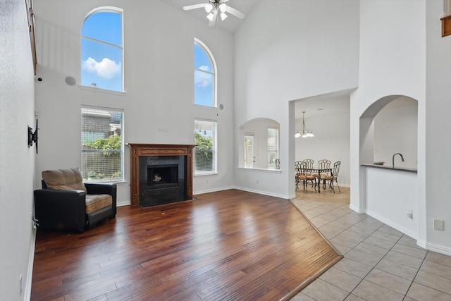 2410 Honey Dr, Arlington, TX 76001 - living room with high vaulted ceiling, ceiling fan, a chandelier, a fireplace with flush hearth, and arched walkways