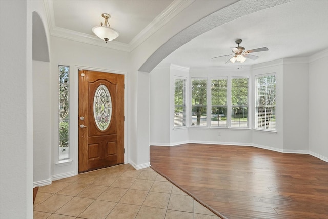 2410 Honey Dr, Arlington, TX 76001 - foyer entrance featuring a ceiling fan, arched walkways, ornamental molding, and light wood-style floors