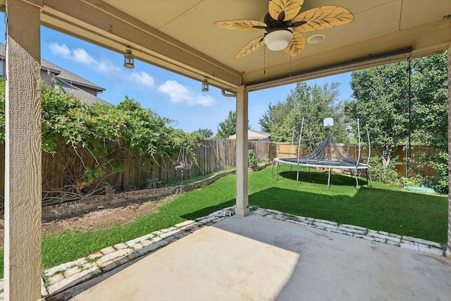 2410 Honey Dr, Arlington, TX 76001 - fenced backyard featuring ceiling fan, a patio, and a trampoline