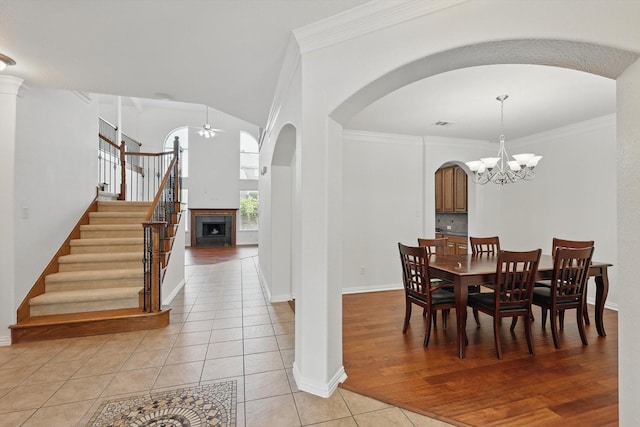 2410 Honey Dr, Arlington, TX 76001 - dining space featuring arched walkways, light tile patterned flooring, a chandelier, stairway, and a ceiling fan