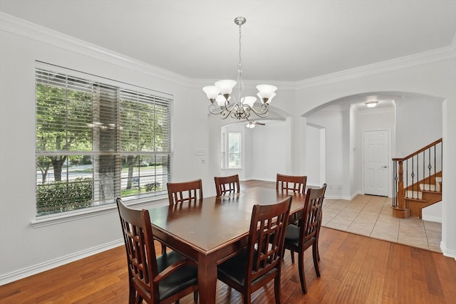 2410 Honey Dr, Arlington, TX 76001 - dining area featuring arched walkways, stairs, a chandelier, crown molding, and light wood-style flooring