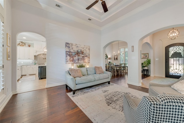 105 Orion Ct, Aurora, TX 76078 - living room featuring a towering ceiling, a ceiling fan, dark wood-style floors, a chandelier, and arched walkways