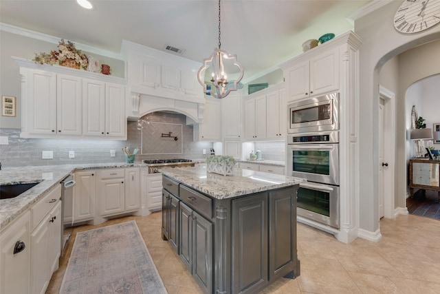 105 Orion Ct, Aurora, TX 76078 - kitchen with gray cabinets, white cabinetry, appliances with stainless steel finishes, arched walkways, and a chandelier