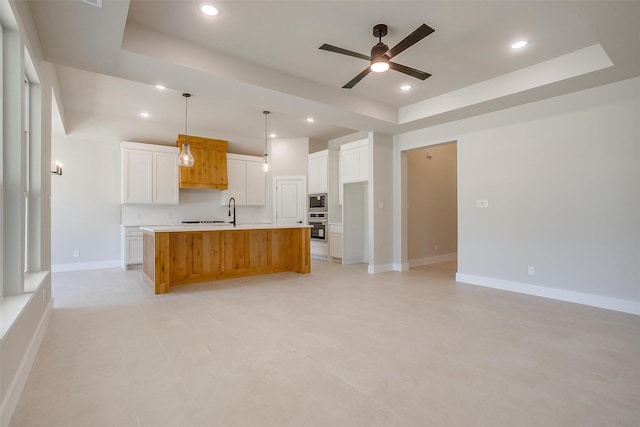 2602 23rd St, Fort Worth, TX 76106 - kitchen featuring appliances with stainless steel finishes, a raised ceiling, ceiling fan, white cabinetry, and a kitchen island with sink