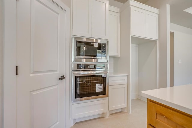 2602 23rd St, Fort Worth, TX 76106 - kitchen with appliances with stainless steel finishes, light tile patterned floors, white cabinetry, and light countertops