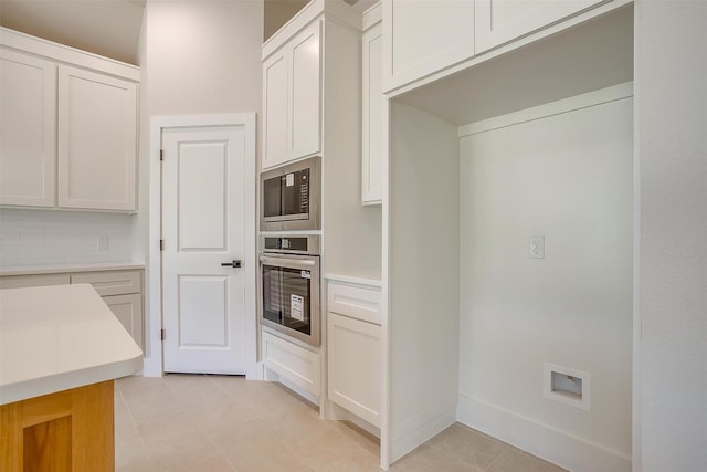 2602 23rd St, Fort Worth, TX 76106 - kitchen with appliances with stainless steel finishes, light tile patterned floors, light countertops, decorative backsplash, and white cabinetry