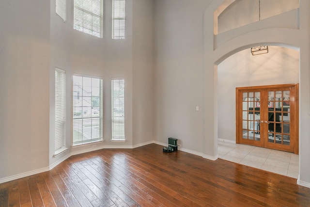 5424 Yellow Birch Dr, Fort Worth, TX 76244 - spare room featuring a towering ceiling, wood-type flooring, french doors, baseboards, and arched walkways