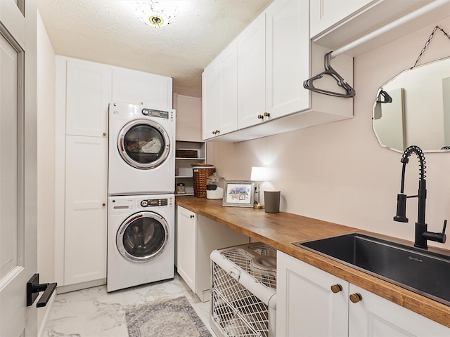 6512 Elkhurst Dr, Plano, TX 75023 - washroom featuring stacked washer / drying machine, cabinet space, light marble finish floors, and a textured ceiling