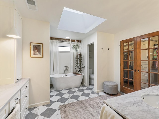 6512 Elkhurst Dr, Plano, TX 75023 - full bath featuring baseboards, a skylight, a freestanding tub, vanity, and toilet