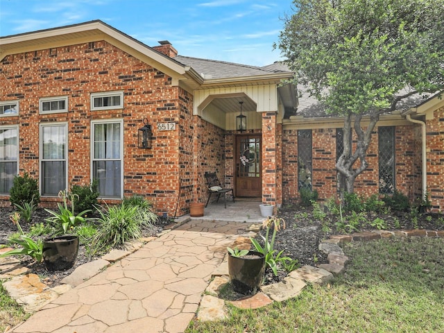 6512 Elkhurst Dr, Plano, TX 75023 - entrance to property featuring brick siding, a shingled roof, and a chimney