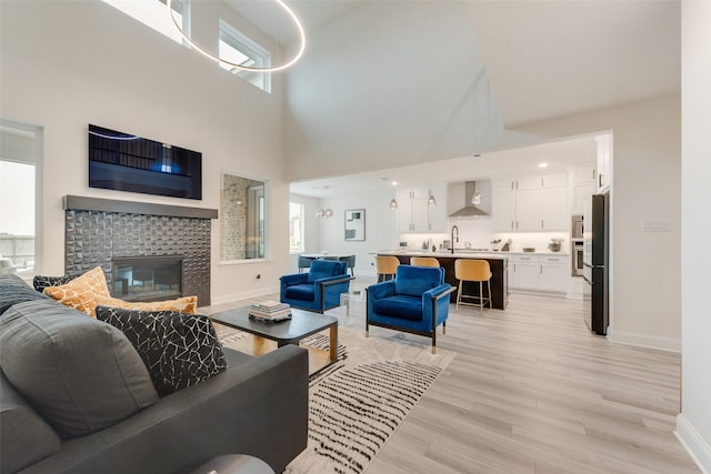 1308 Redbrick Ln, Northlake, TX 76247 - living area with baseboards, a towering ceiling, light wood-type flooring, and a tiled fireplace