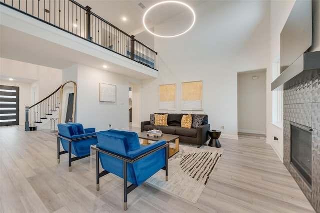 1308 Redbrick Ln, Northlake, TX 76247 - living room with a towering ceiling, stairway, baseboards, a glass covered fireplace, and light wood-type flooring
