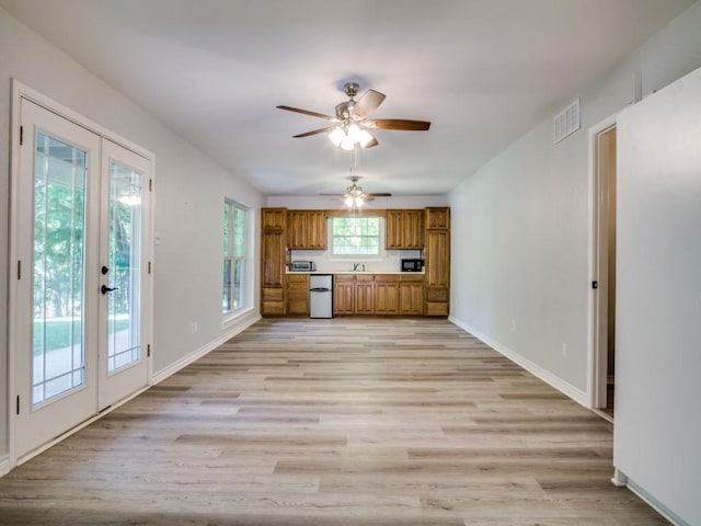 7710 Ravenswood Rd, Granbury, TX 76049 - kitchen with brown cabinetry, a ceiling fan, dishwashing machine, light wood finished floors, and french doors