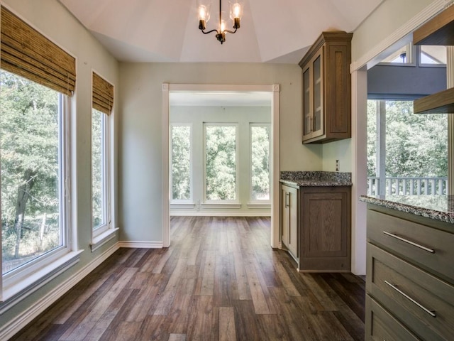7710 Ravenswood Rd, Granbury, TX 76049 - kitchen featuring light stone countertops, plenty of natural light, a chandelier, and glass insert cabinets