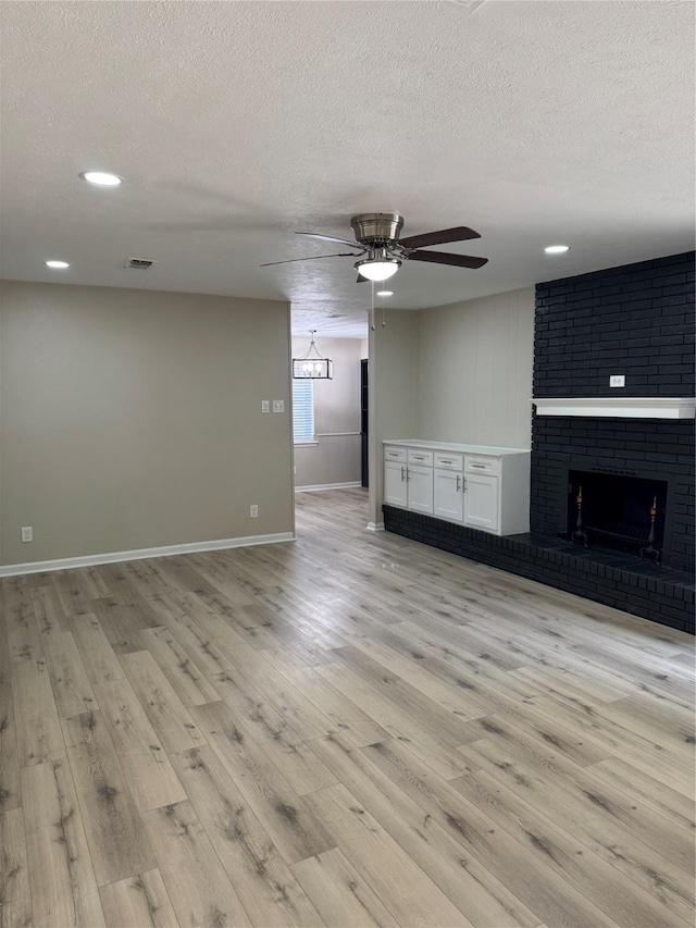 711 S Farmington Rd, Howe, TX 75459 - unfurnished living room featuring a textured ceiling, a ceiling fan, light wood-style flooring, baseboards, and a brick fireplace
