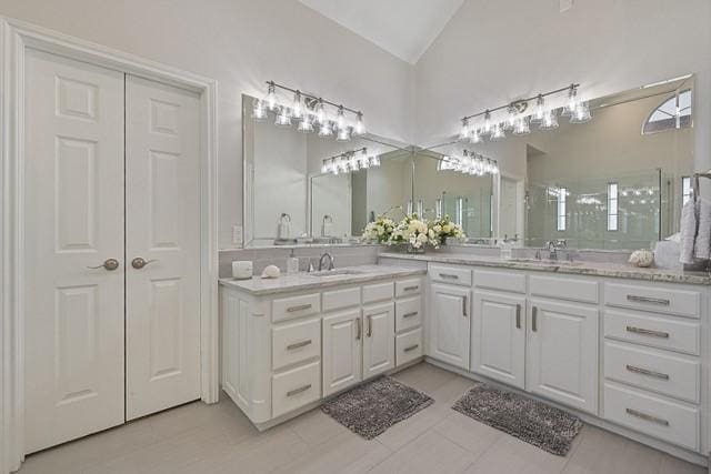 711 Saratoga Dr, Southlake, TX 76092 - bathroom featuring vanity, vaulted ceiling, a shower, and tile patterned flooring