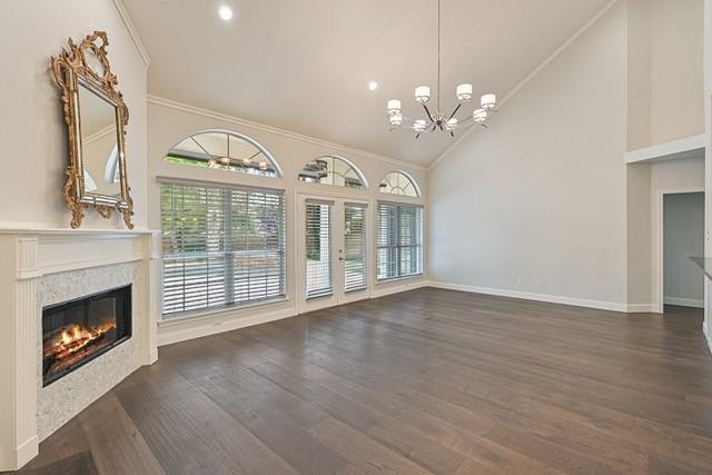 711 Saratoga Dr, Southlake, TX 76092 - unfurnished living room with a glass covered fireplace, ornamental molding, a chandelier, plenty of natural light, and wood finished floors