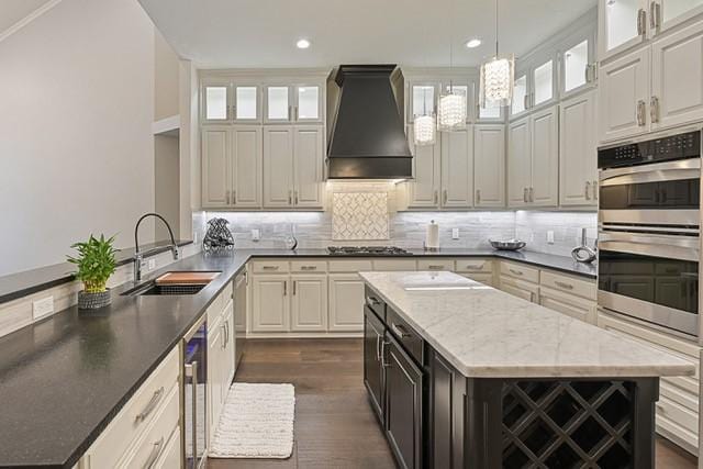 711 Saratoga Dr, Southlake, TX 76092 - kitchen with a sink, custom exhaust hood, double oven, a kitchen island, and beverage cooler