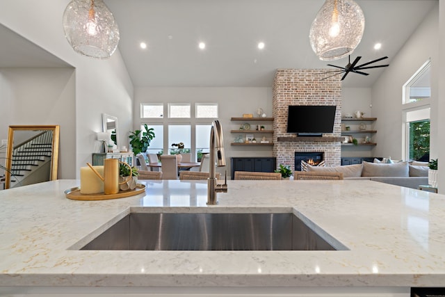 410 Travelers Ter, Argyle, TX 76226 - kitchen featuring a brick fireplace, open floor plan, a ceiling fan, a sink, and high vaulted ceiling