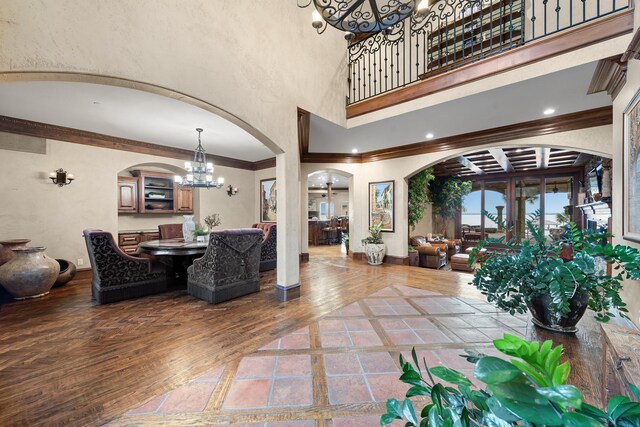 1612 S Lakeshore Dr, Rockwall, TX 75087 - living room featuring a chandelier, arched walkways, a high ceiling, hardwood / wood-style floors, and crown molding