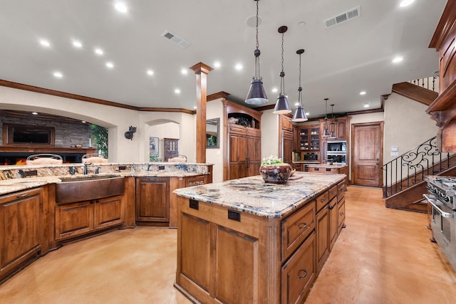 1612 S Lakeshore Dr, Rockwall, TX 75087 - kitchen featuring a sink, brown cabinets, ornamental molding, a kitchen island, and light stone countertops