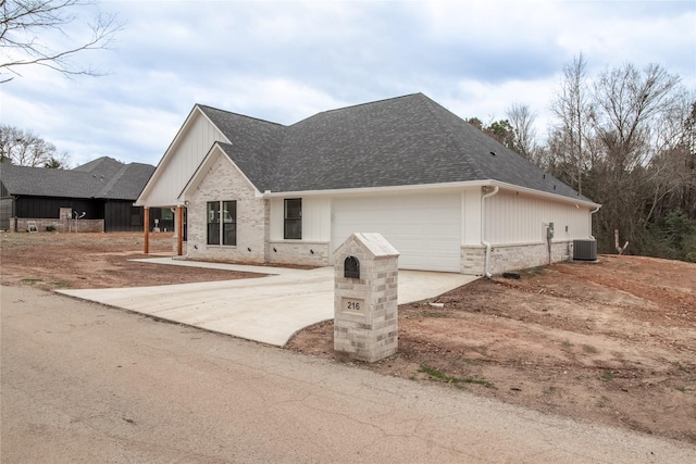 216 Pauline St, Arp, TX 75750 - view of front of home with concrete driveway, brick siding, a garage, central AC unit, and roof with shingles