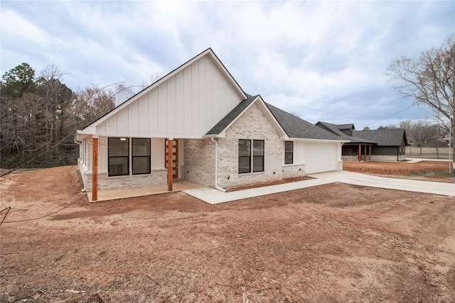 216 Pauline St, Arp, TX 75750 - back of house with concrete driveway, an attached garage, brick siding, board and batten siding, and a shingled roof