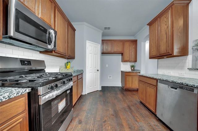 1102 Mccormick St, Garland, TX 75040 - kitchen featuring stainless steel appliances, brown cabinetry, decorative backsplash, light stone counters, and ornamental molding