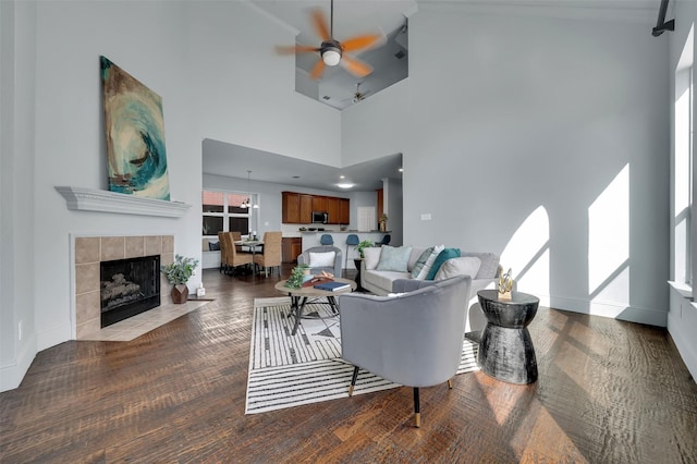 1102 Mccormick St, Garland, TX 75040 - living room featuring a ceiling fan, a fireplace, baseboards, wood finished floors, and a towering ceiling