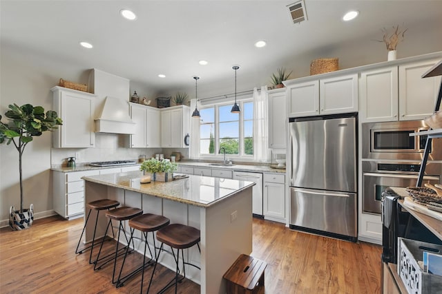 261 Casa Blanca Ave, Fort Worth, TX 76107 - kitchen featuring stainless steel appliances, custom range hood, recessed lighting, white cabinets, and a kitchen bar