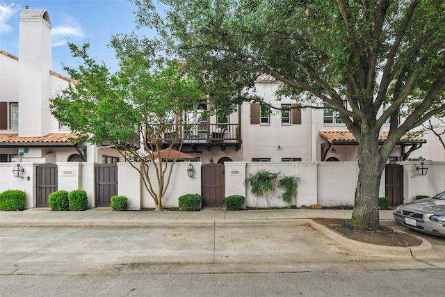 261 Casa Blanca Ave, Fort Worth, TX 76107 - view of front of house featuring a gate, a tiled roof, a fenced front yard, stucco siding, and a balcony