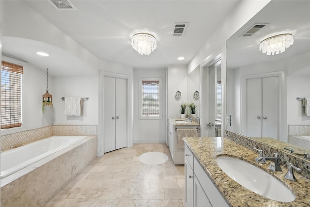 261 Casa Blanca Ave, Fort Worth, TX 76107 - bathroom featuring a chandelier, two vanities, a garden tub, and recessed lighting