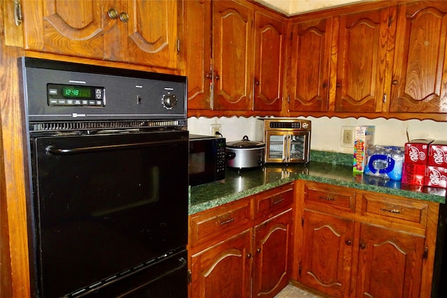 212 E Kearney St, Mesquite, TX 75149 - kitchen with black appliances, brown cabinetry, and dark countertops