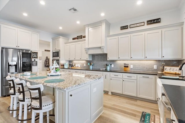 10116 T Bury Ln, Waco, TX 76708 - kitchen with appliances with stainless steel finishes, crown molding, decorative backsplash, a kitchen bar, and custom exhaust hood