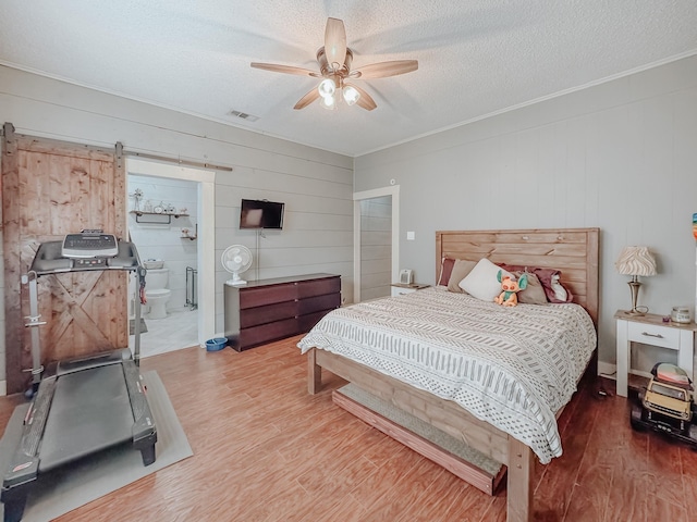 1530 W 5th Ave, Corsicana, TX 75110 - bedroom featuring wood walls, wood finished floors, ornamental molding, a textured ceiling, and a barn door