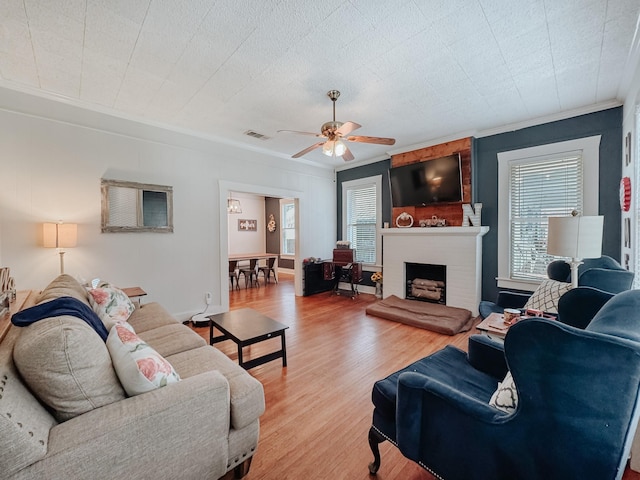 1530 W 5th Ave, Corsicana, TX 75110 - living area featuring ornamental molding, plenty of natural light, a ceiling fan, light wood-style floors, and a fireplace