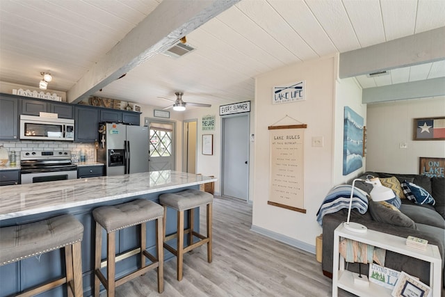 166 Ocean Dr, Gun Barrel City, TX 75156 - kitchen with stainless steel appliances, a breakfast bar area, backsplash, light wood-style flooring, and light stone countertops