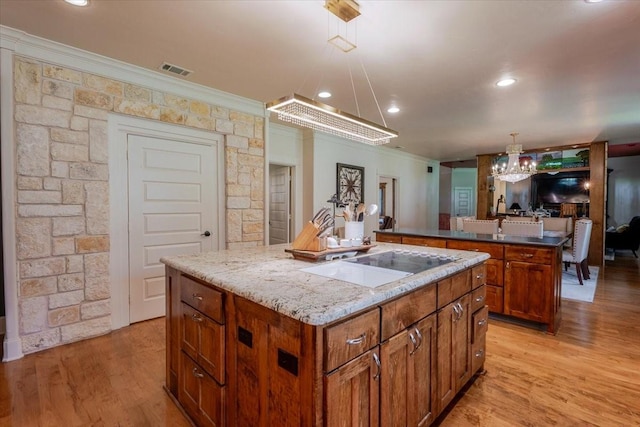 121 Big Jake Ct, Weatherford, TX 76088 - kitchen with a kitchen island, crown molding, electric cooktop, brown cabinets, and a chandelier