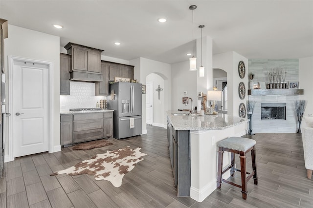 4444 Blue Mist Dr, Fort Worth, TX 76036 - kitchen featuring stainless steel appliances, a sink, arched walkways, a breakfast bar, and light stone counters