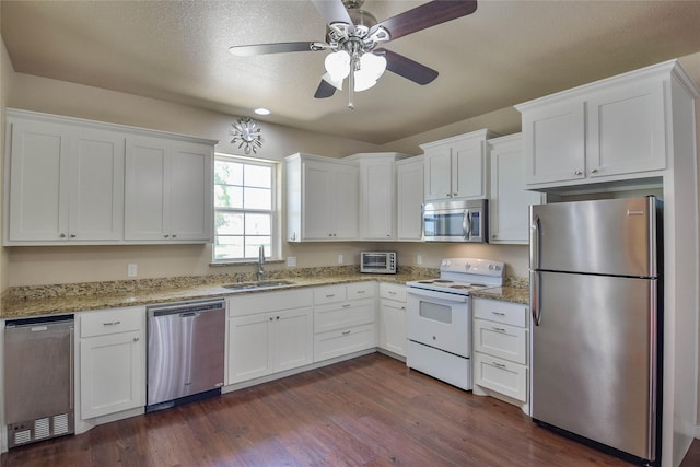 6495 Smoky Hill Ct, Granbury, TX 76049 - kitchen with stainless steel appliances, a sink, white cabinets, dark wood finished floors, and a ceiling fan